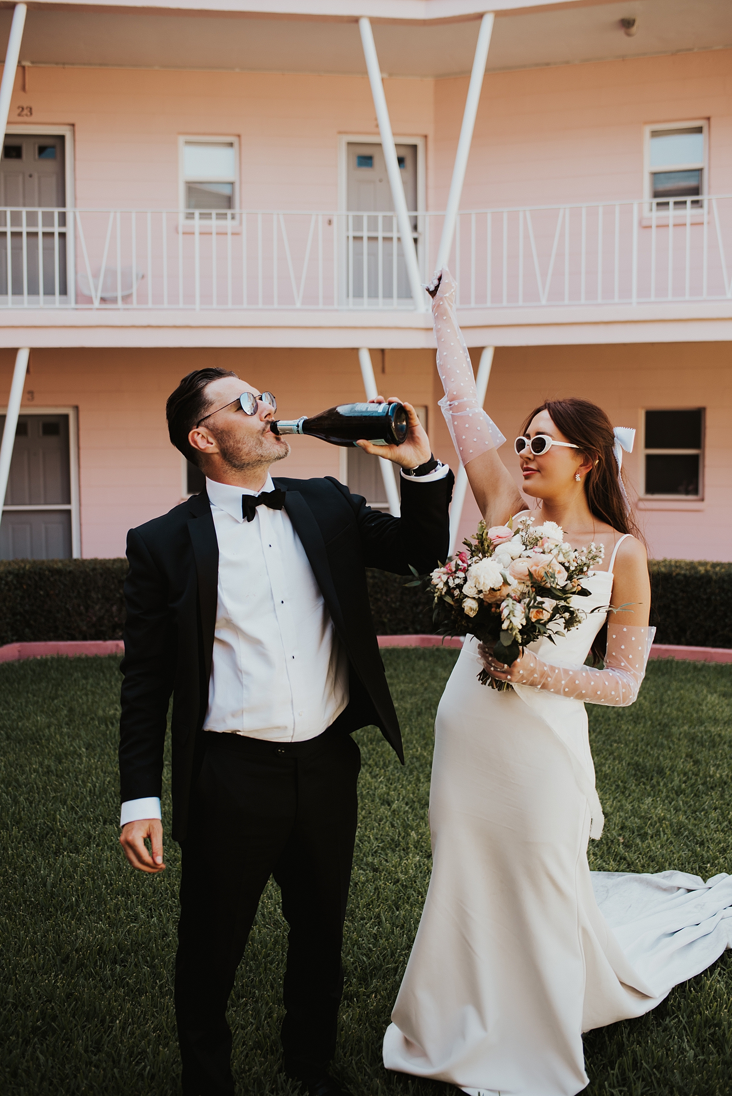 Groom drinking from a bottle of champagne while bride cheers him on after their Orlando elopement
