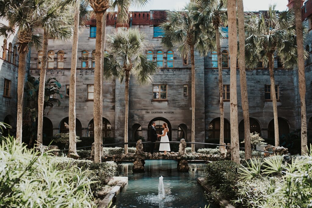 Bride and groom exchanging vows on a stone bridge in the middle of the Lightner Museum courtyard