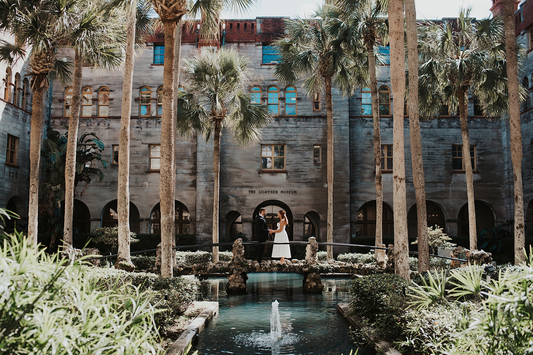 Bride and groom exchanging vows on a stone bridge in the middle of the Lightner Museum courtyard
