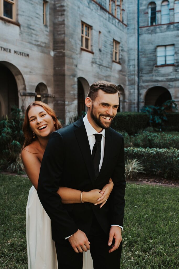Bride and groom laughing in front of the gardens of the Lightner Museum courtyard