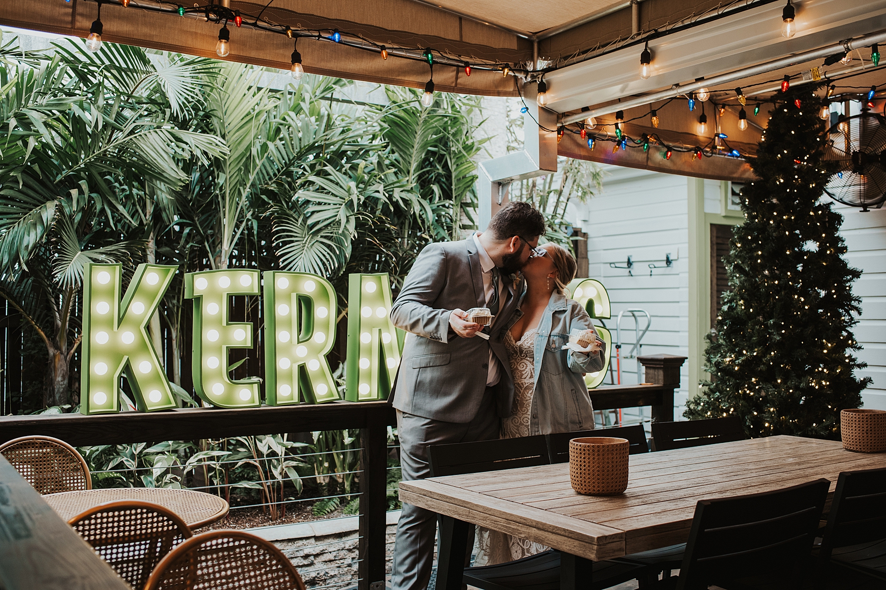 Couple kissing in front of Kermit's lighted sign as they eat their key lime pie during their Key West elopement