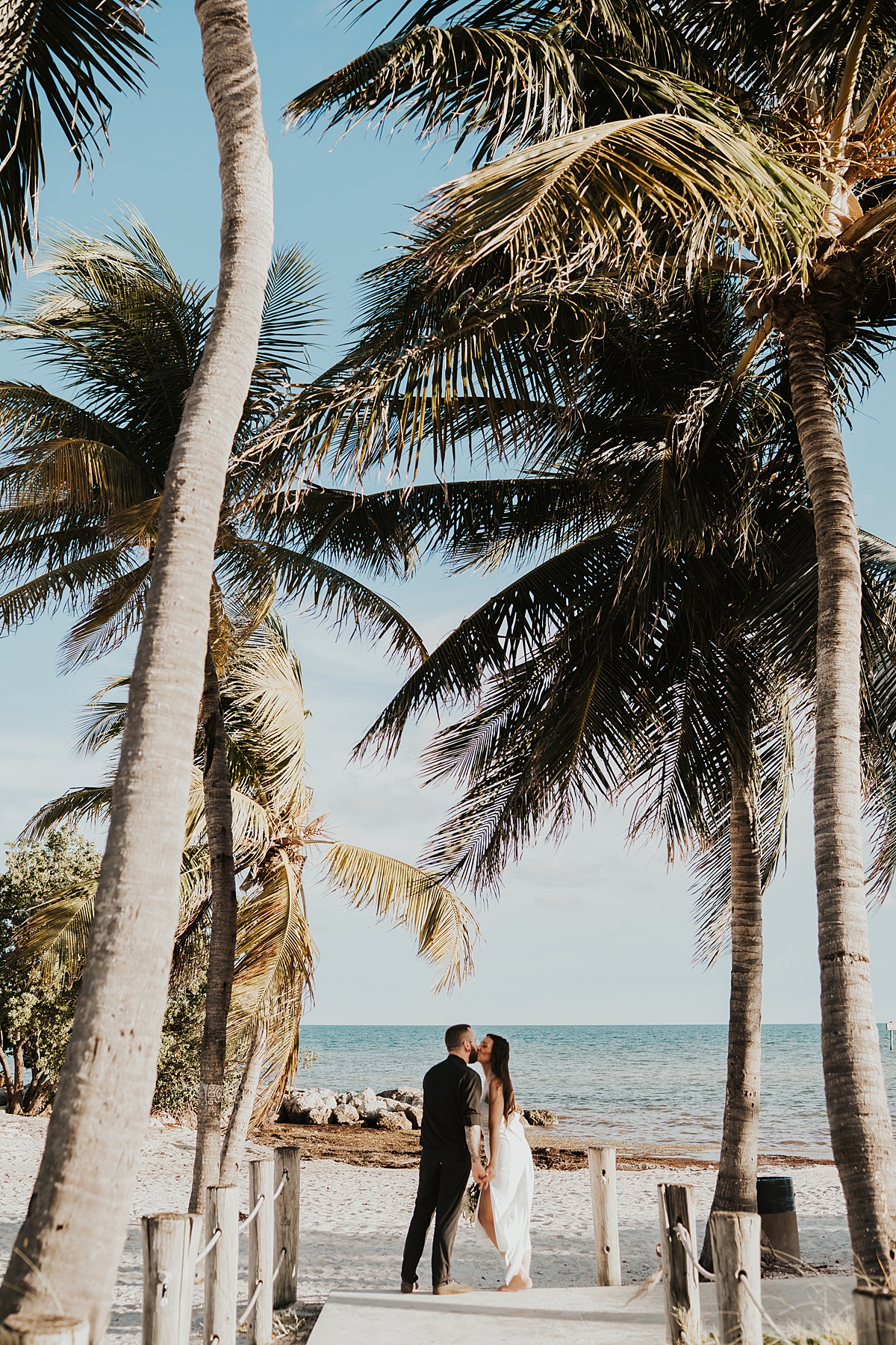 Bride and groom stopping for a kiss on a beach access after their Key West elopement on Smathers Beach in September