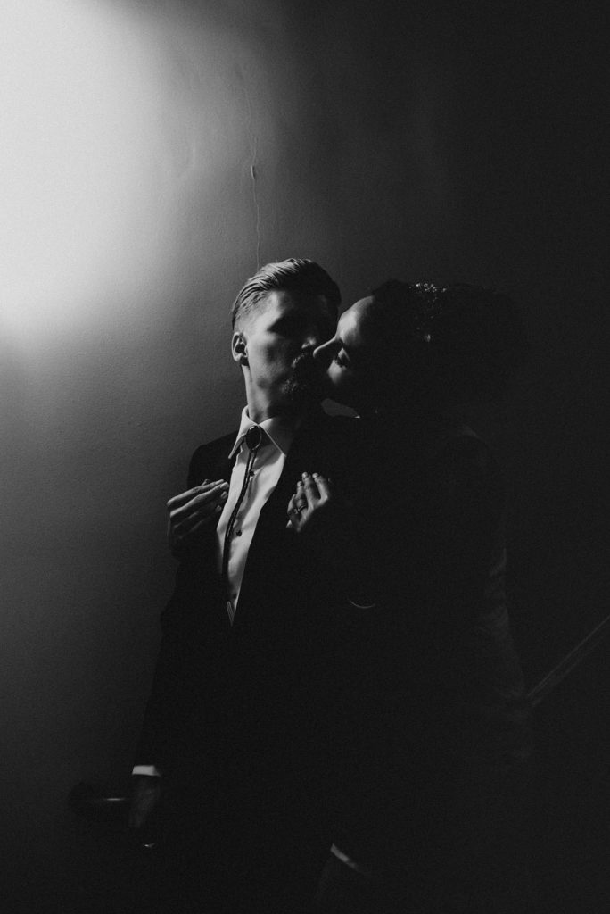 Dramatic black and white of groom kissing bride over his shoulder