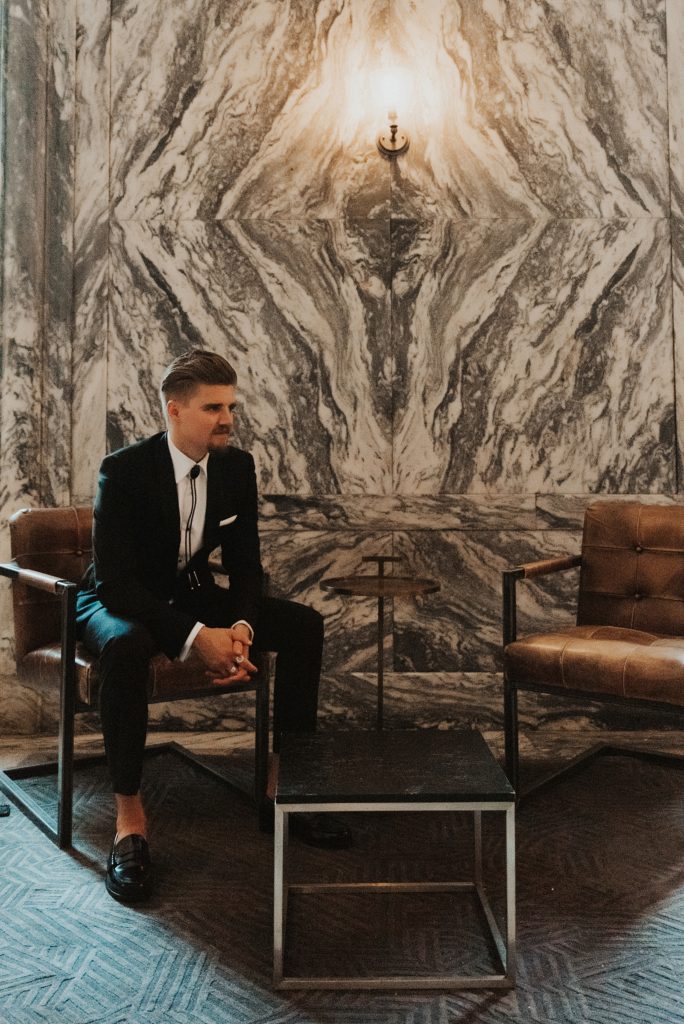 Groom sitting in front of marble wall at Le Meridien tampa