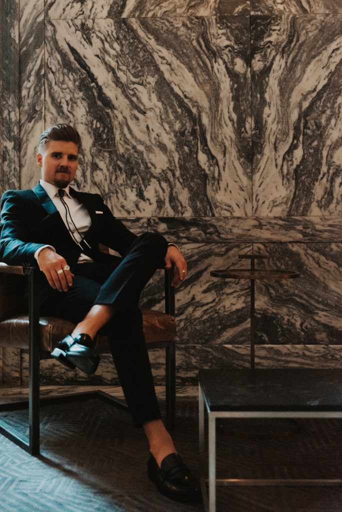 Groom sitting in front of marble wall at Le Meridien tampa
