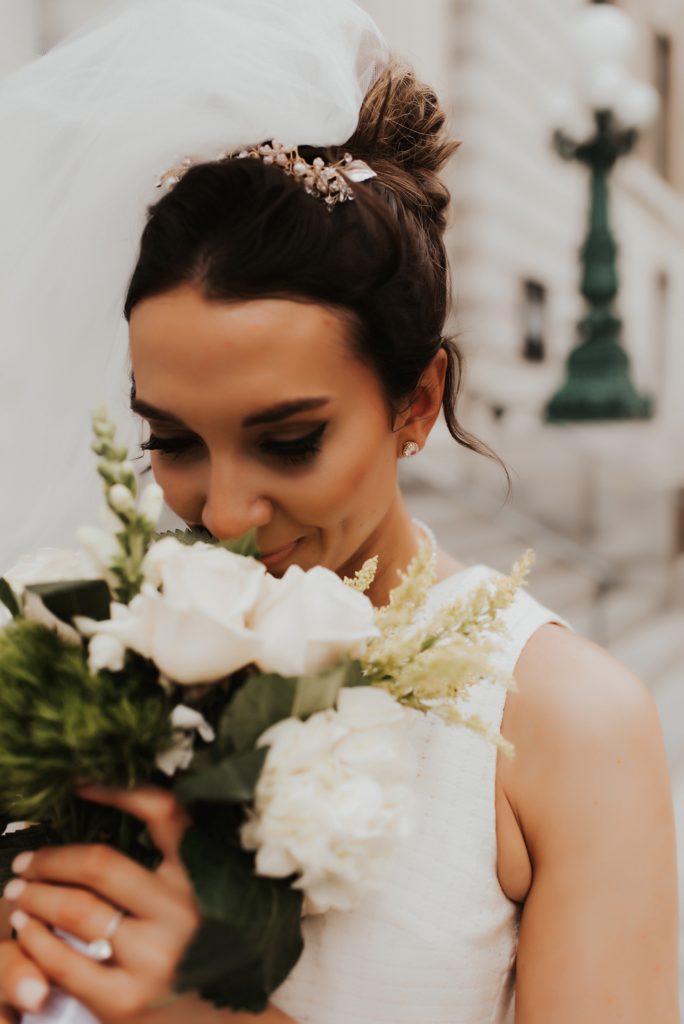 Bride in short veil smelling bouquet