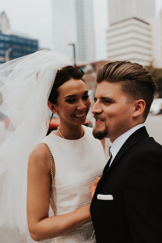 Bride nuzzling into grooms cheek on downtown street