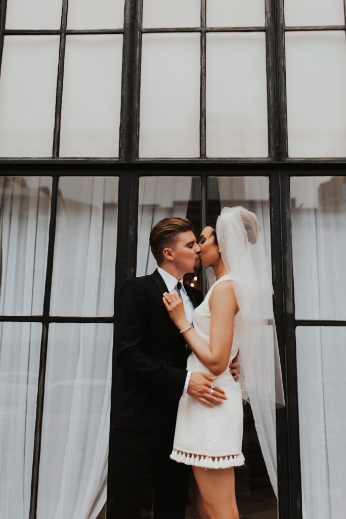 Bride and groom kissing in front of downtown Tampa window