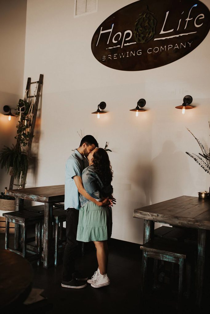 Couple kissing during engagement session inside brewery