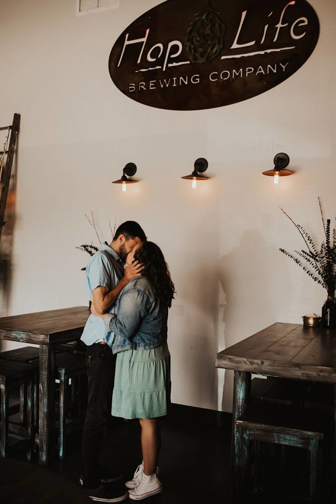 Couple kissing during engagement session inside brewery