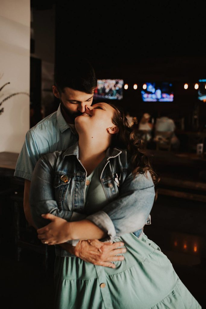 Couple cuddling during engagement session inside brewery