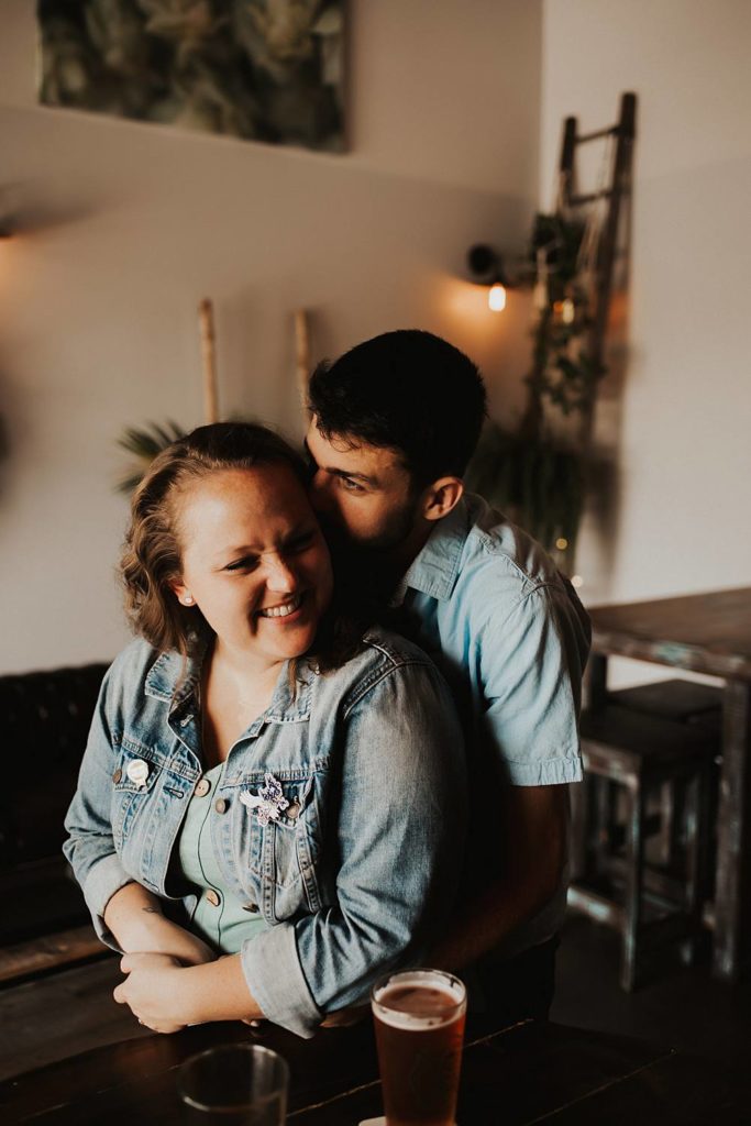 Couple hugging during engagement session inside brewery