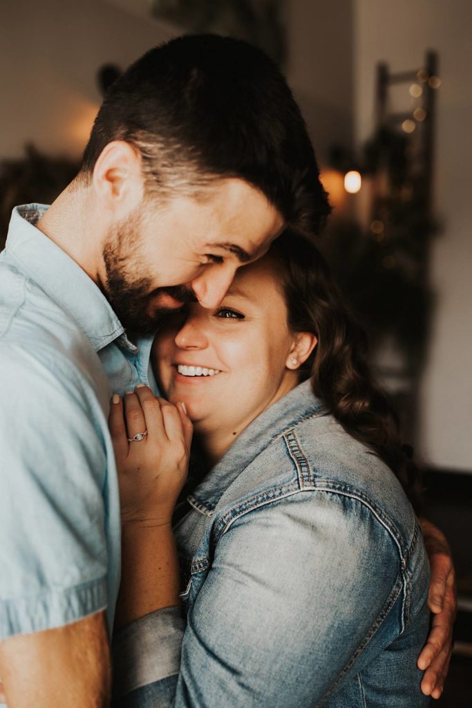 Couple cuddling during engagement session inside brewery
