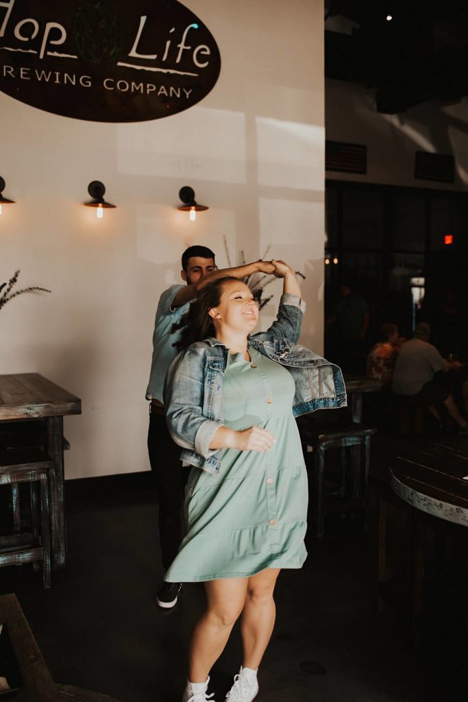 Couple dancing during engagement session inside brewery