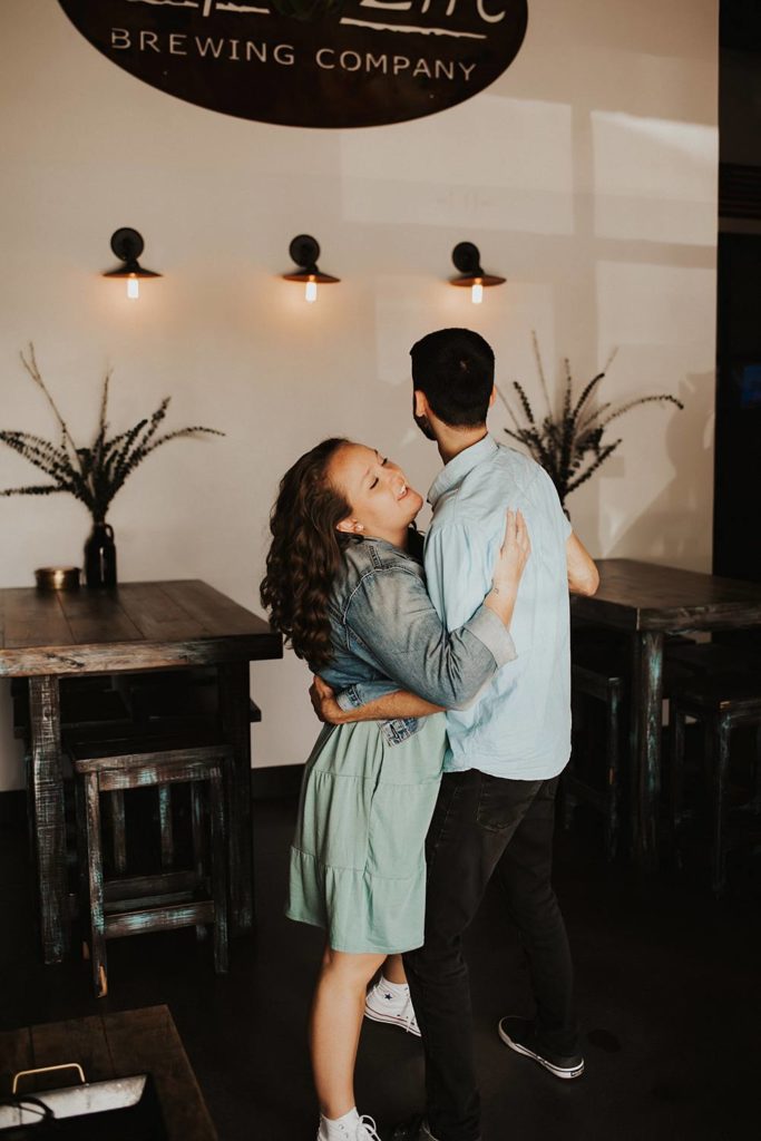 Couple dancing during engagement session inside brewery