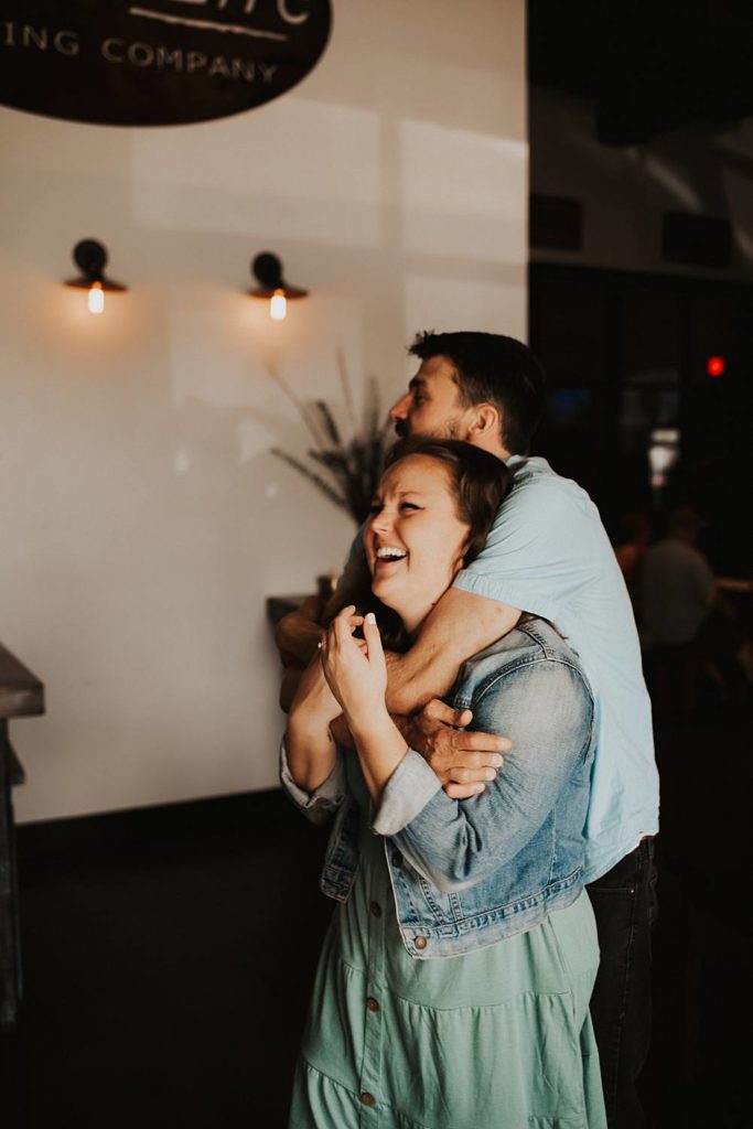 Couple laughing during engagement session inside brewery