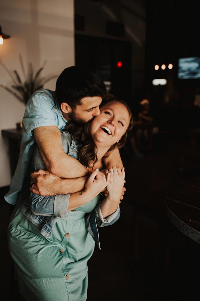 Couple laughing during engagement session inside brewery