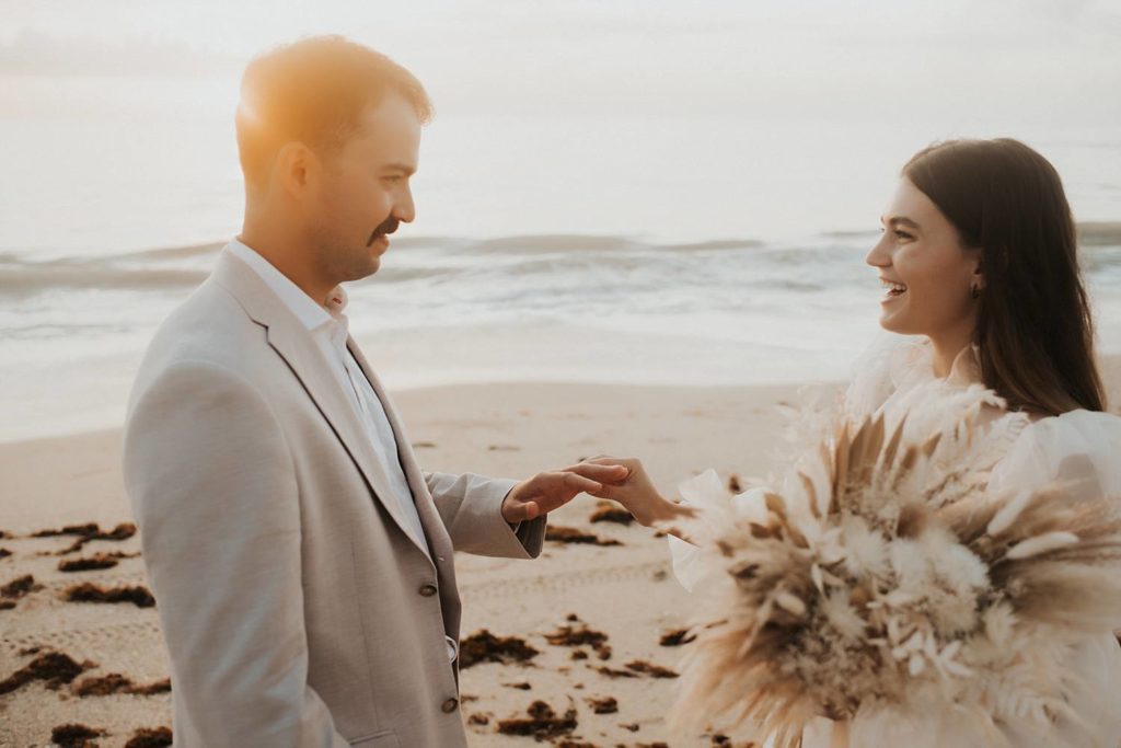 Bride and groom exchanging rings on beach