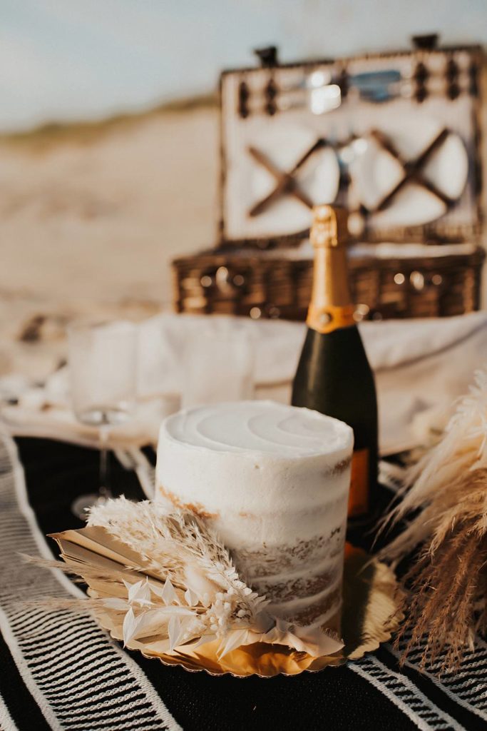 Mini layered cake with dried flowers and champagne on the beach