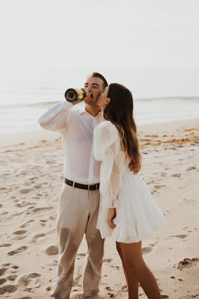 Groom drinking champagne on the beach