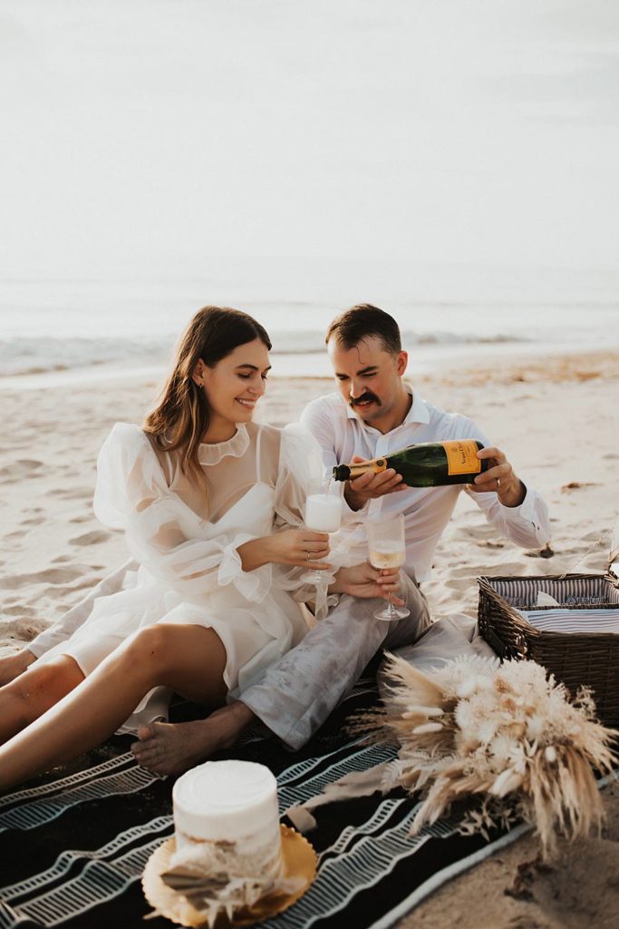 Groom pouring champagne during elopement picnic