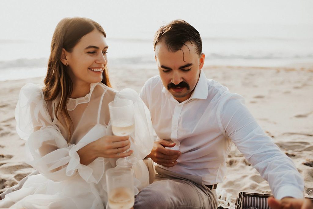 Groom pouring champagne during elopement picnic
