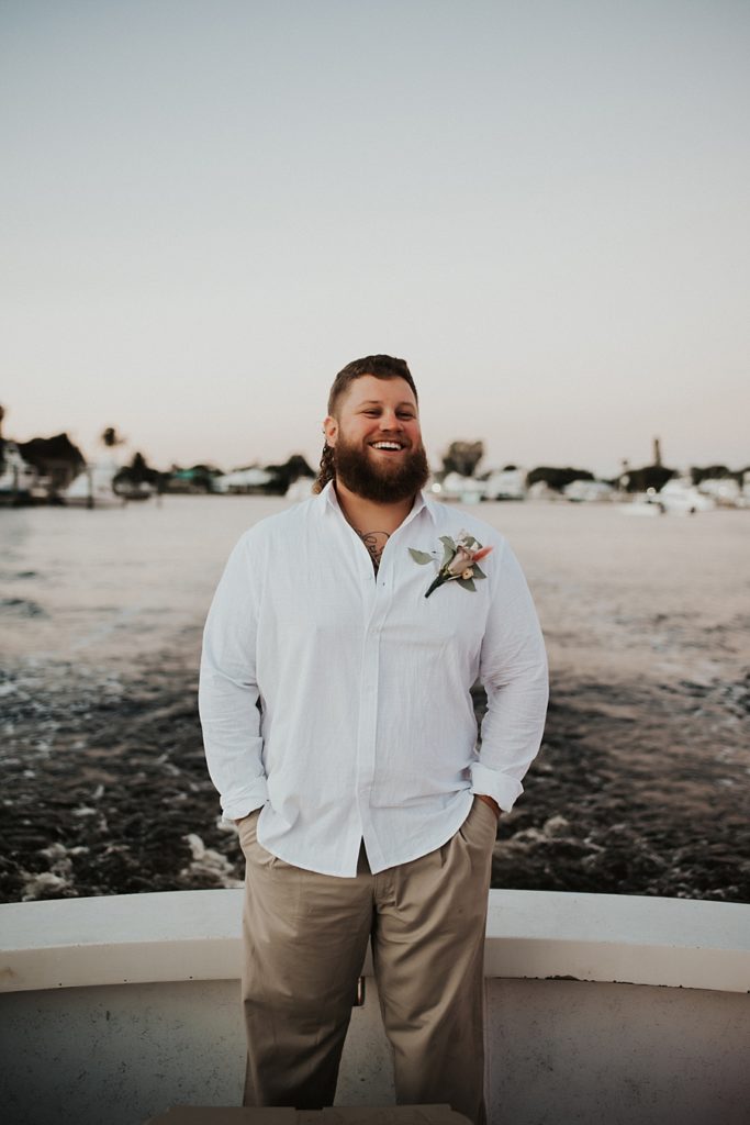 Groom smiling on the back of a boat