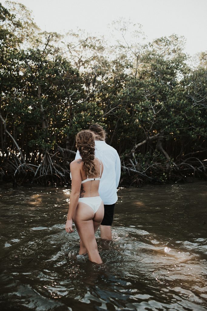 Groom leading bride into mangroves during elopement