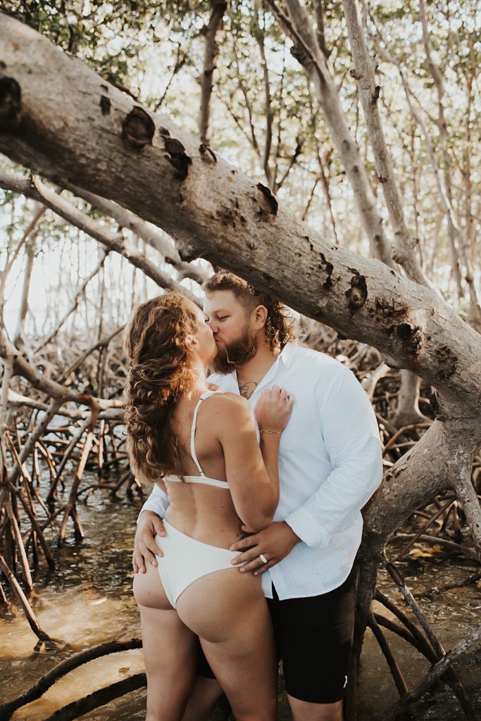 Bride in bikini kissing groom in mangroves