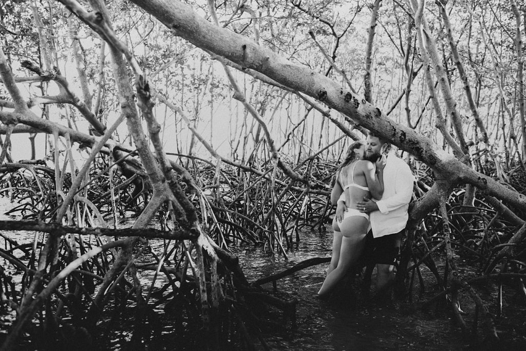 Bride in bikini kissing groom in mangroves