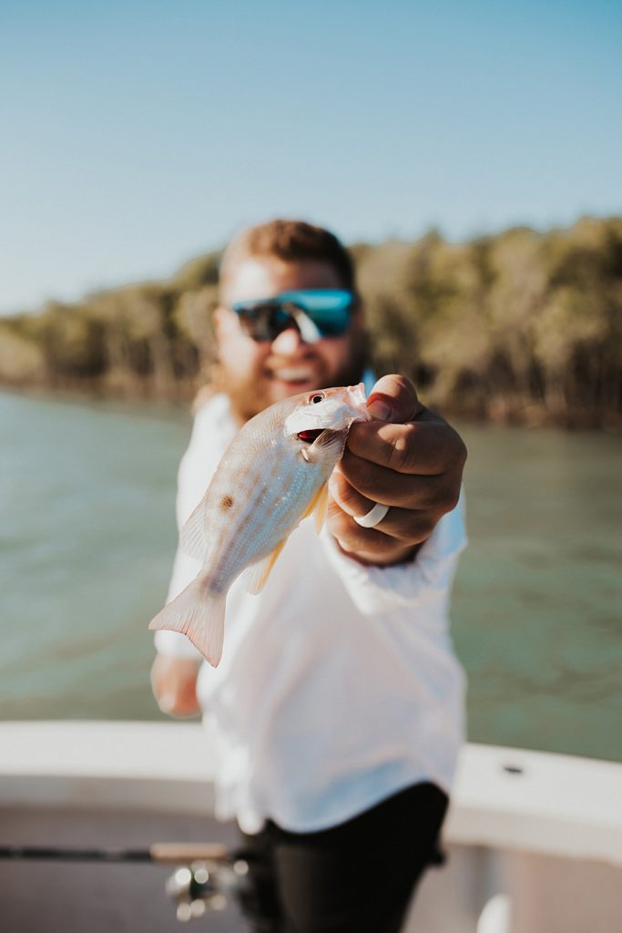 Groom holding up fish during elopement