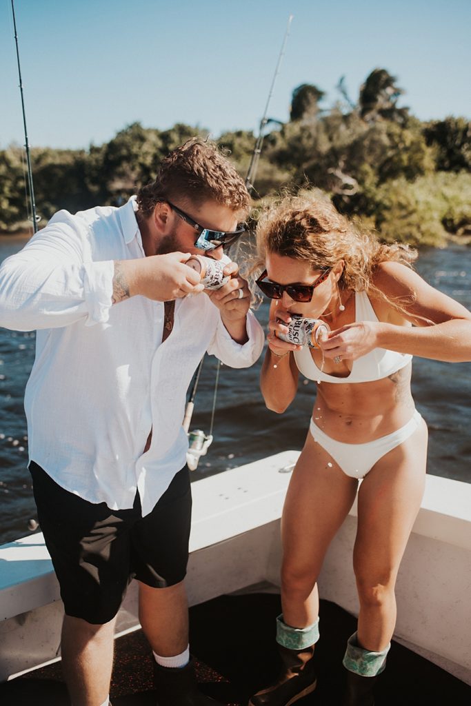 Bride and groom shotgunning beer on back of boat