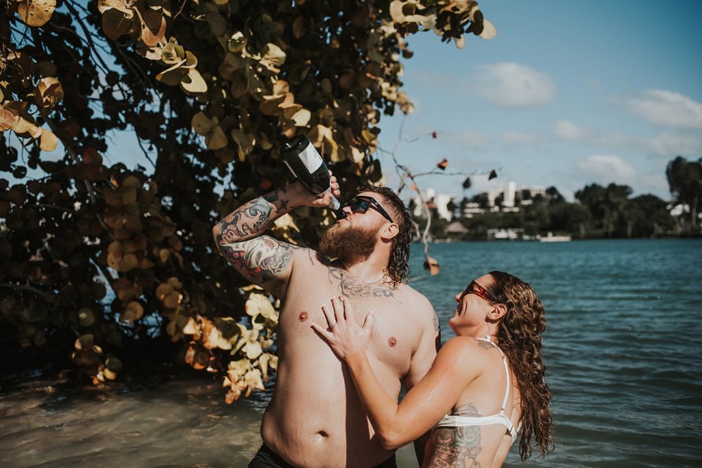 Bride popping champagne in water in front of mangroves