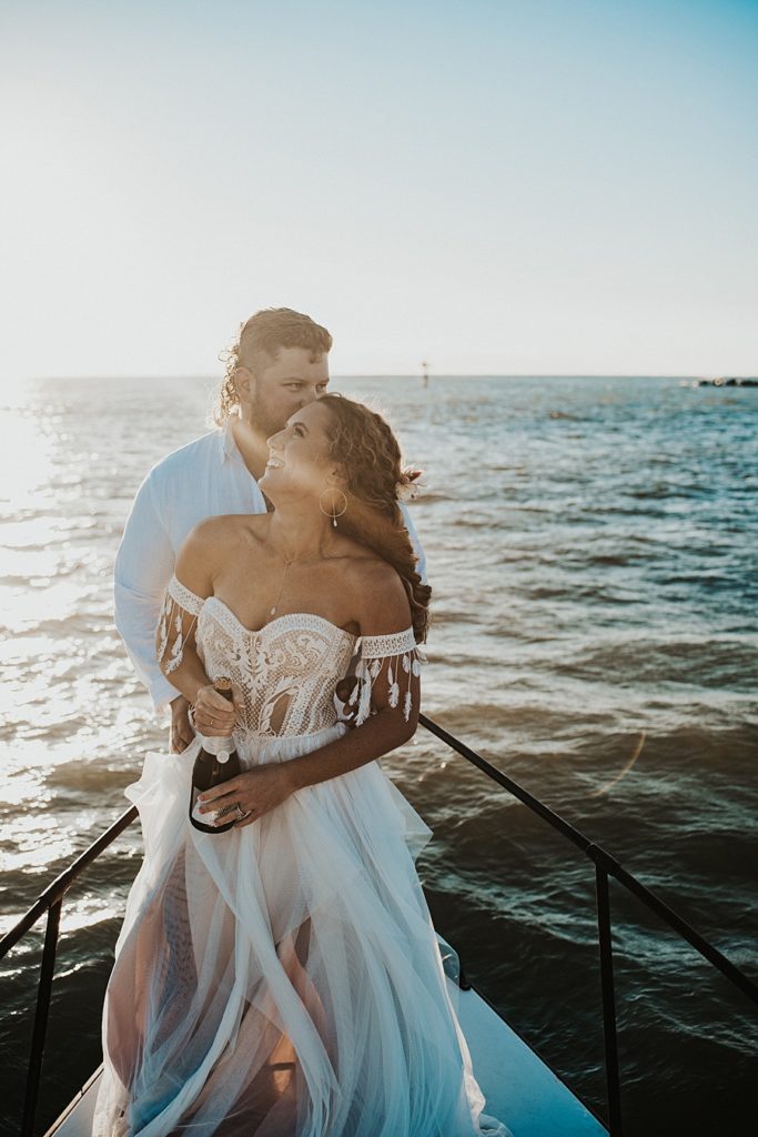 Bride and groom cuddling on front of boat