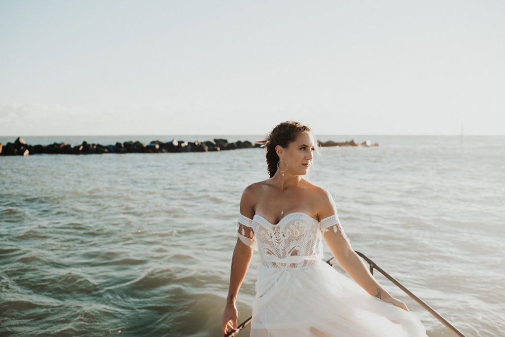 Bride in corset wedding dress with arm cuffs on boat