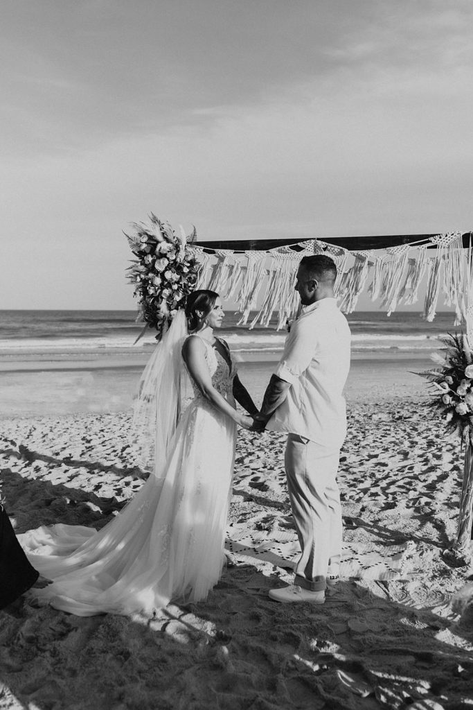 Bride and groom holding hands at beach wedding
