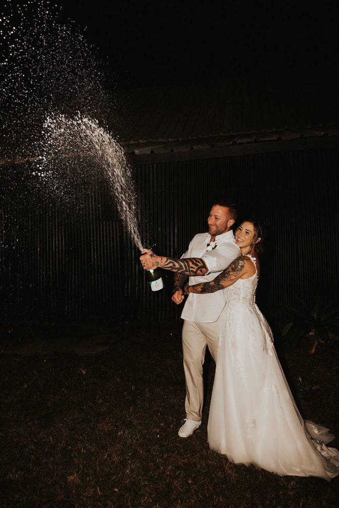 Bride and groom popping champagne at night