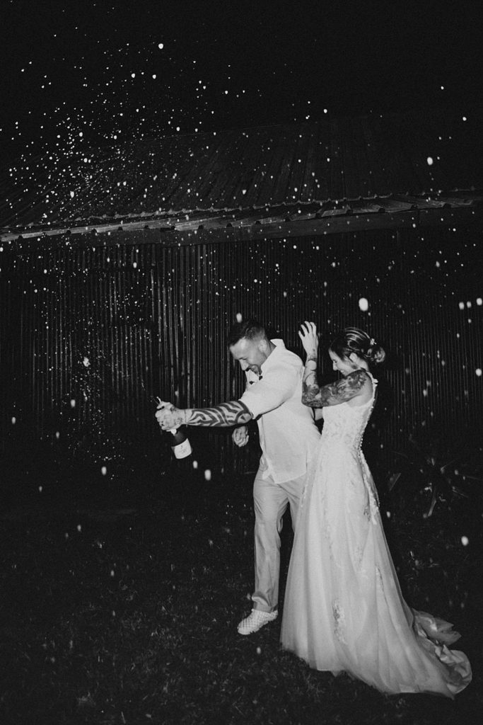 Bride and groom popping champagne at night