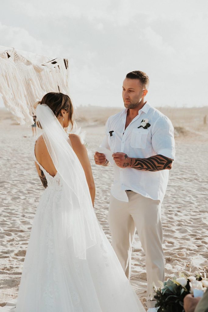 Groom reading vows to bride at beach wedding
