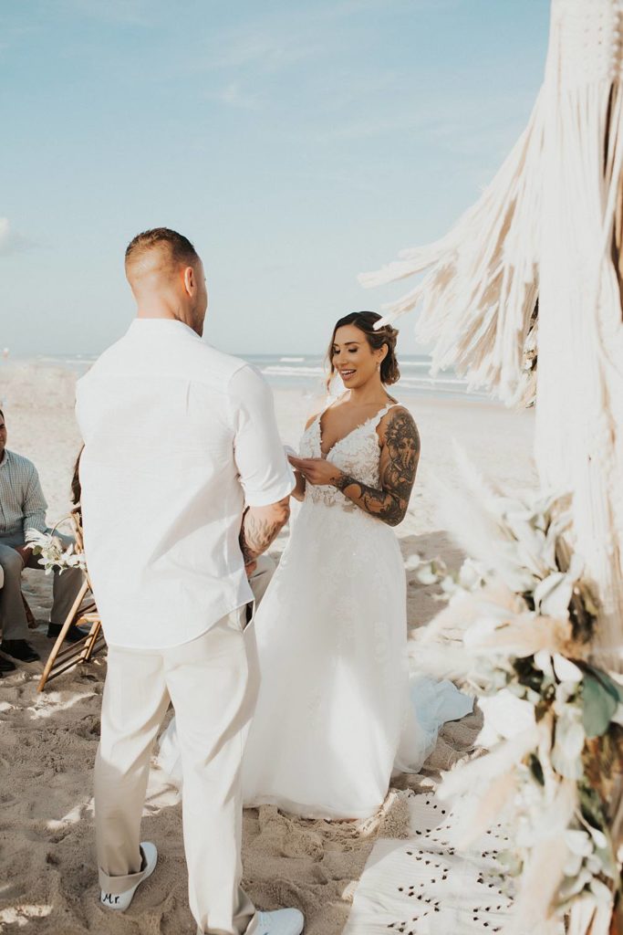 Bride reading vows to groom at beach wedding