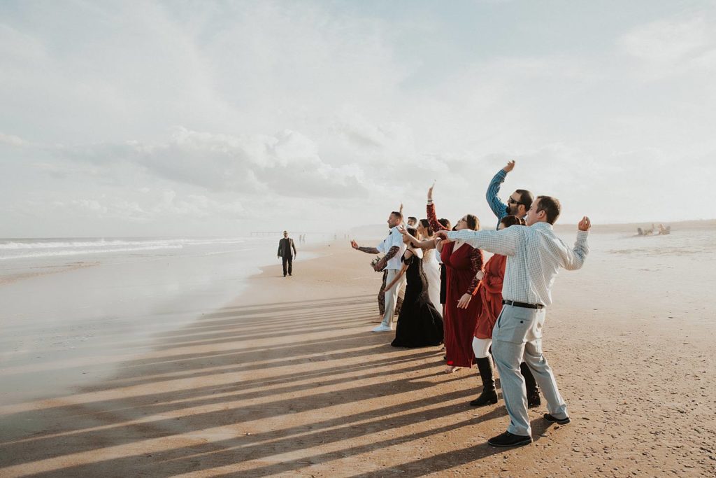 Wedding guests throwing stones into ocean