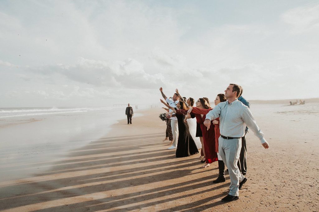 Wedding guests throwing stones into ocean