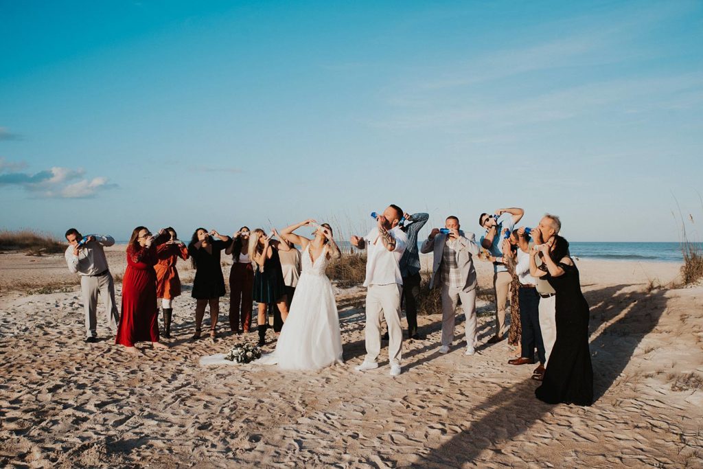 Wedding guests shotgunning beer after beach ceremony