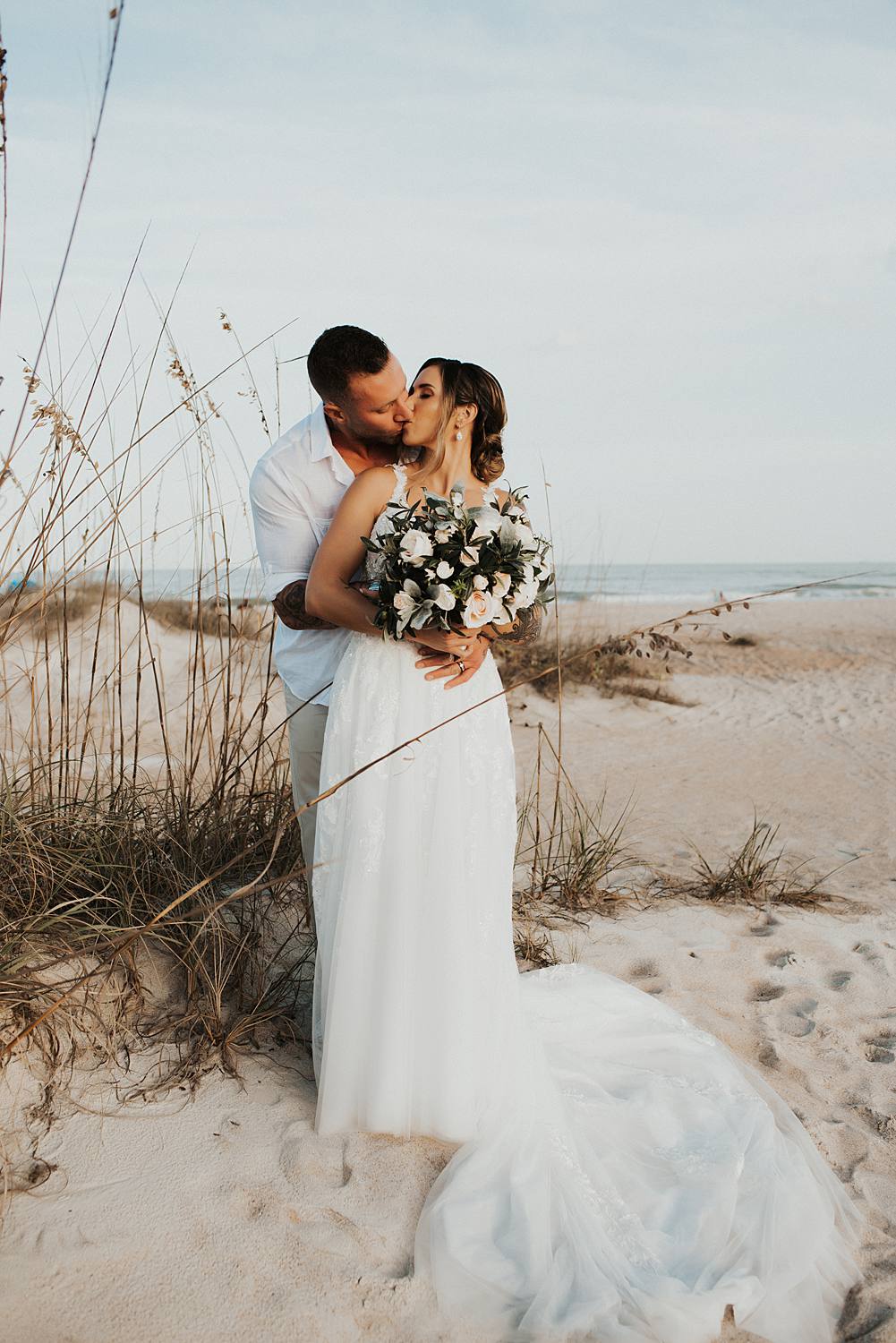 Bride and groom kissing on beach