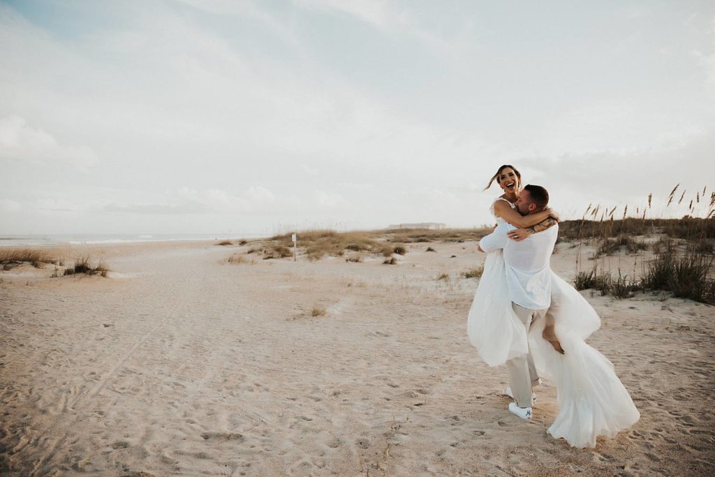 Bride jumping on groom on beach