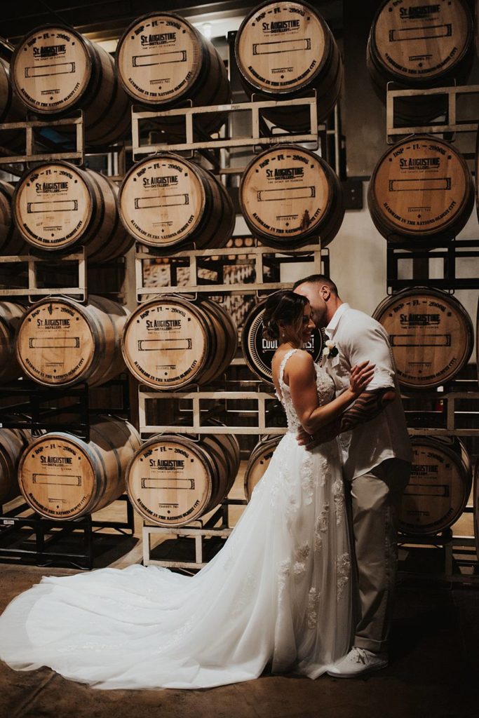 Bride and groom in front of barrels at Saint Augustine Distillery