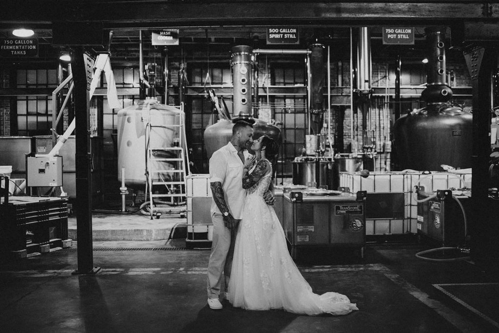 Bride and groom kissing in front of distillery