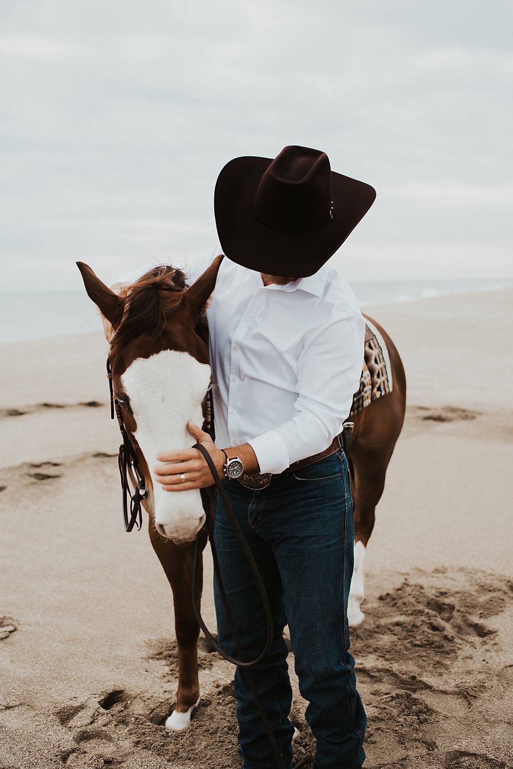 Groom petting horse on the beach