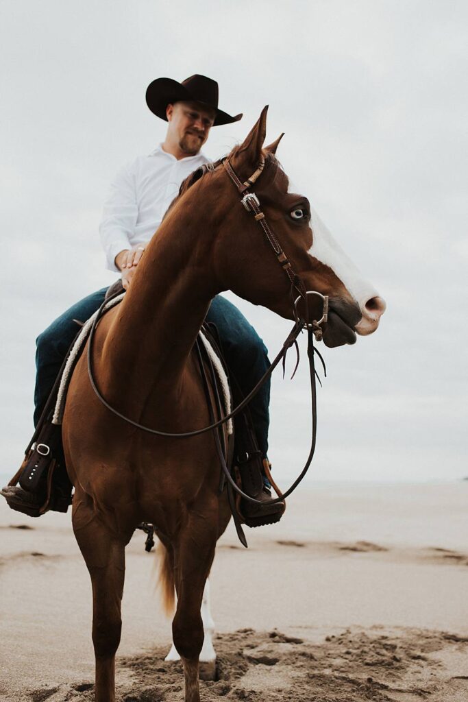 Groom sitting on horse at the beach