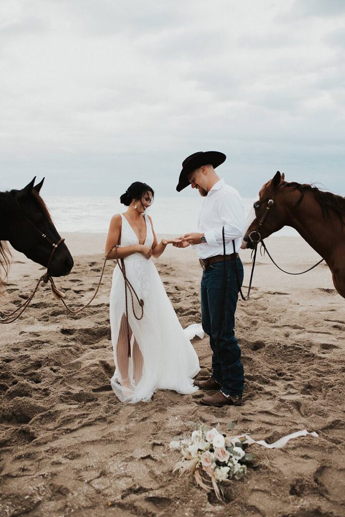 Bride and groom exchanging rings on Florida beach during their elopement with their horses